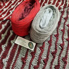 two skeins of yarn sitting on top of a red and white blanket