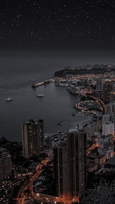 an aerial view of a city at night with boats in the water and buildings lit up