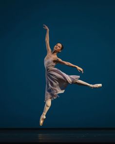 a ballerina in the air with her arms outstretched