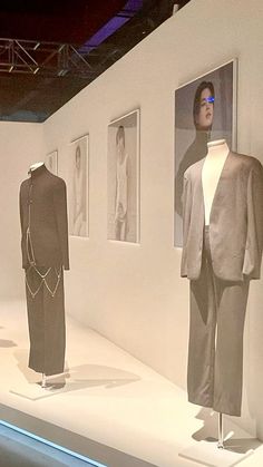 three mannequins are on display in an art gallery, one is wearing a suit