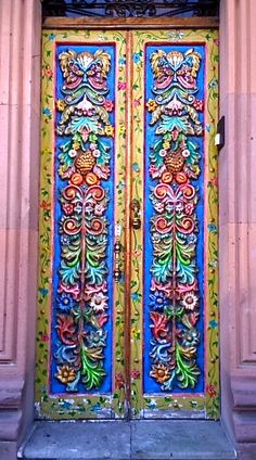 an ornately painted wooden door on the side of a building