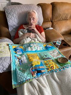 an older woman sitting on a couch with a quilt