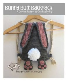 a crocheted bag hanging on a hanger with a pom pom