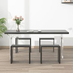 a table and two chairs in a room with white walls, wood flooring and a potted plant