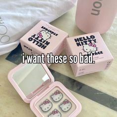 three pink hello kitty boxes sitting on top of a table next to a cup and mirror