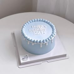 a blue birthday cake sitting on top of a white table next to a box with the number twenty