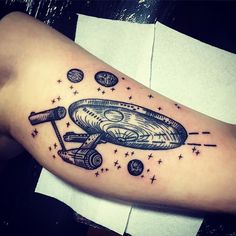 a tattoo on the arm of a man with a spaceship and stars around it in black ink