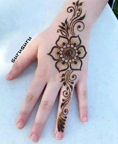 a woman's hand with henna tattoos on it, and an intricate flower design