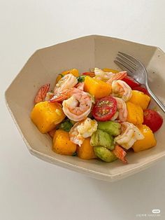 a bowl filled with shrimp, oranges and cucumbers next to a fork