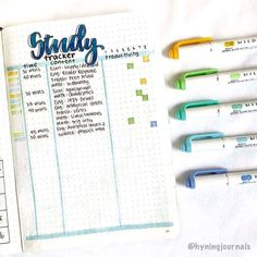 an open planner with four pens on top of it and the words study tracker written in cursive writing