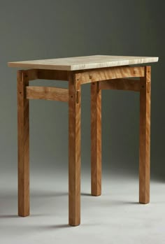 a wooden table sitting on top of a white floor next to a gray wall in front of it