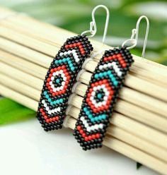 two beaded earrings sitting on top of wooden sticks