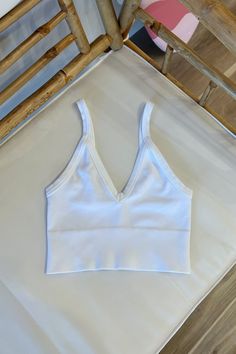 Ribbed v-neck bra top with thick hems. 92% Nylon 8% Spandex | Hand wash cold One size Made in USA White Seamless V-neck Top, White Seamless V-neck Crop Top, White Bra-friendly Low-cut Top, White Low-cut Bra-friendly Top, Bra Friendly White Low-cut Top, Seamless Stretch V-neck Crop Top, Spring V-neck High Stretch Crop Top, White Stretch Triangle Top Tank, Fitted V-neck Seamless Crop Top