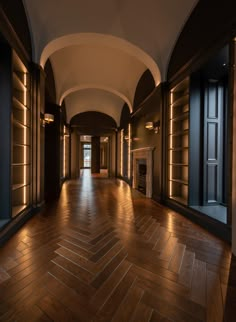 an empty hall with wooden floors and walls, lit by recessed lights on either side