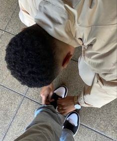 a man standing on top of a tile floor next to a person with an afro