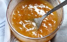 a spoon in a glass bowl filled with orange sauce