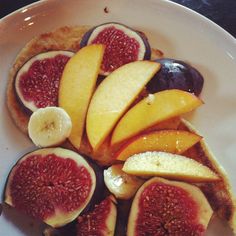 a white plate topped with sliced fruit on top of bread next to a knife and fork