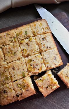 a cutting board topped with squares of cake next to a pair of knife's blades