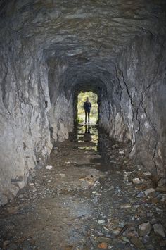 a man is standing in the middle of a tunnel with rocks and gravel on both sides