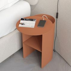 an orange table with a magazine on it next to a couch and lamp plugged into the wall