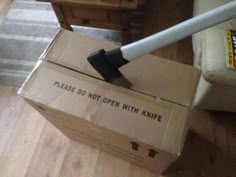 an open box sitting on the floor with a vacuum in it's mouth and a stick sticking out of it