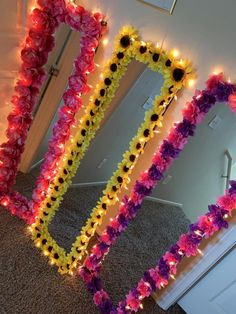 three flower leis in front of a mirror with lights on them and one is pink, yellow and purple