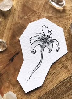 a piece of paper with an image of a flower on it sitting on top of a wooden table