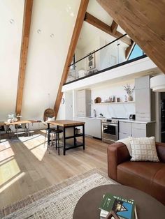 an open living room and kitchen area in a loft style home with wooden beams on the ceiling