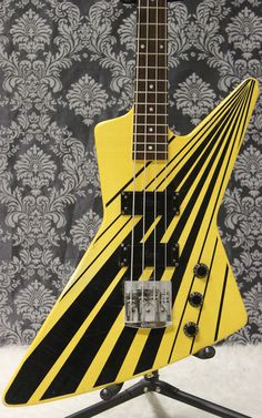 a yellow and black guitar sitting on top of a stand