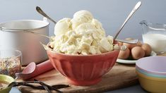 a bowl filled with ice cream sitting on top of a wooden cutting board next to bowls and utensils