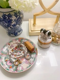 a white and blue vase filled with flowers next to a plate on a counter top