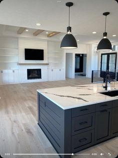 a large kitchen with an island in the middle and two pendant lights hanging from the ceiling