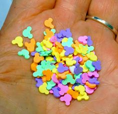 a person's hand is full of small multicolored teddy bear shaped confetti