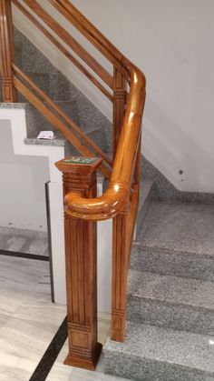 a wooden hand rail on the side of a stair case next to a tiled floor