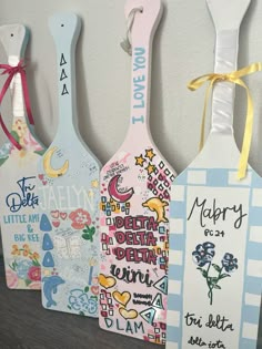 three wooden spoons with different designs on them hanging from the side of a wall