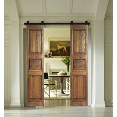 an open wooden door leading to a dining room with white walls and wood trimmings