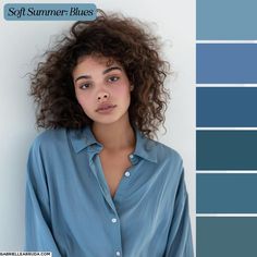 a woman with curly hair wearing a blue shirt and standing in front of a white wall