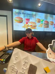 a woman standing in front of a counter at a fast food restaurant with a fake hamburger on it