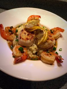 a white plate topped with shrimp and grits