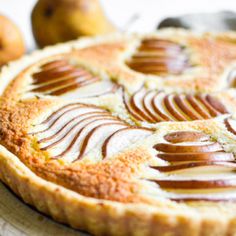 there is a pie with caramel on it and some pears in the background