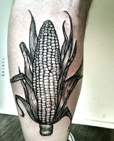 a corn on the cob tattoo is shown in black and grey ink, while it's still attached to a mans leg