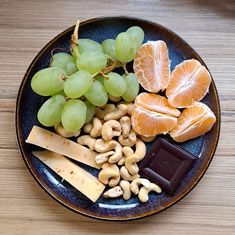 grapes, nuts, and oranges are arranged on a blue plate with some chocolate