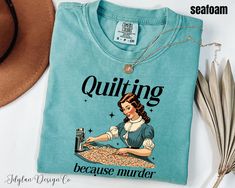 a t - shirt with an image of a woman sewing on it, next to some feathers