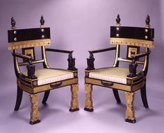 two chairs sitting side by side in front of a purple background with gold trimming