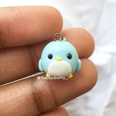 a small blue bird charm sitting on top of a persons finger