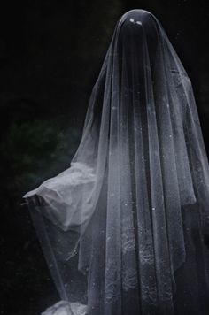 a veiled woman is standing in the dark