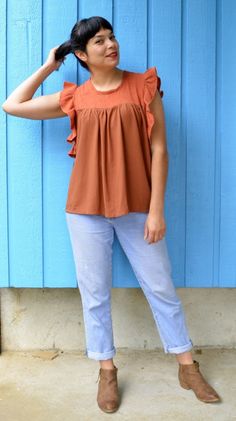 a woman standing in front of a blue wall with her hands on her head and looking up