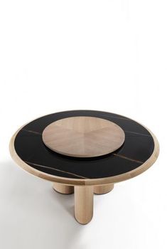 a black and wood table with a circular wooden plate on it's center piece