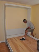 a man standing in an empty room with hard wood flooring and walls painted yellow