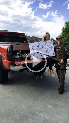 a man and woman standing in front of a truck holding a sign that says,